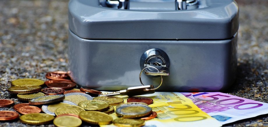 Eine Geldkassette aus Metall mit Scheinen und Münzen darin