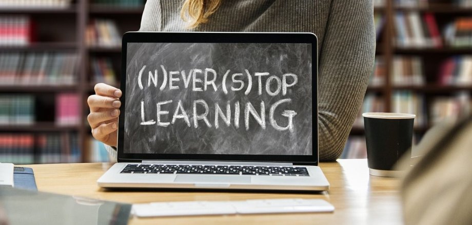 Frau hält den englischen Schriftzug "Never stop learning."