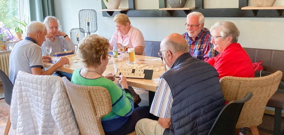 Senioren sitzen am Tisch und spielen 