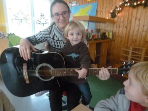 Musik spielt eine große Rolle. Hier hat eine Erzieherin ein Kind und eine Gitarre auf dem Schoß.