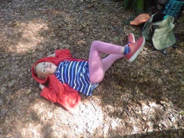 Foto: Ein Kindergartenkind liegt auf einem mit Blättern bedeckten Waldboden