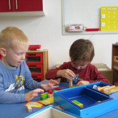 Kinder basteln am Tisch mit Bauklötzen