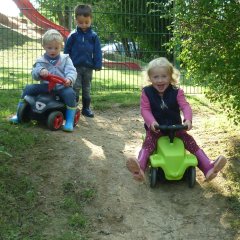 Kinder fahren im Garten mit dem Bobbycar