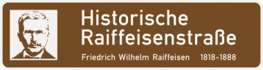 Ein Foto der braun-weißen Straßenschilder mit der Aufschrift "Historische Raiffeisenstraße". 